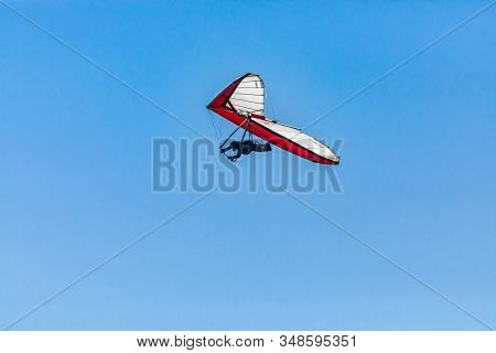 Overhead View Of Flying Hang-gliding Against The Clear Blue Sky. Hang Glider Flying Soaring On A Sun