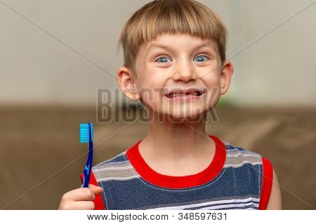 The Boy Holds A Toothbrush In His Hand Showing Clean Teeth