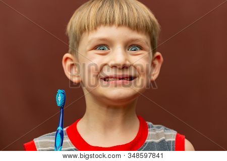 A Smiling And Joyful Boy Holds A Toothbrush In His Hand