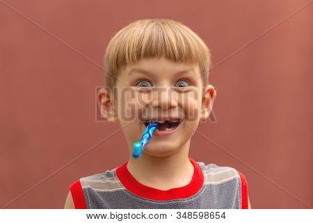 Joyful Child With A Toothbrush In His Mouth Wide Open Looking At The Camera