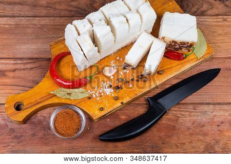 Pieces Of Partly Cut Salted Pork Fatback On Skin Lie On The Wooden Cutting Board Among The Some Spic