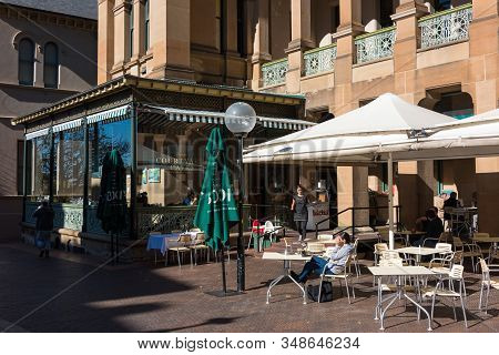 Sydney, Australia - July 3, 2016: Courtyard Cafe With People Relaxing And Waitress Bringing Patrons 