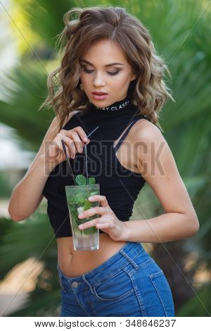 Beautiful Young Woman Enjoy Enjoys A Smoothie And Relax On Tropical Beach With Palm Tree. Summer Vac