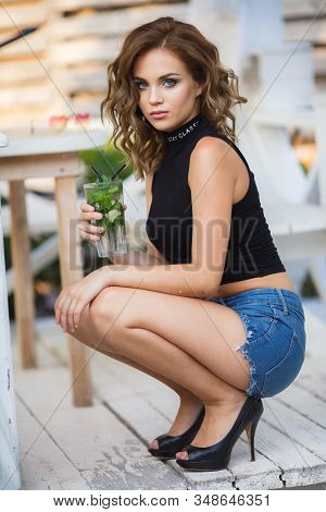 Beautiful Young Woman Enjoy Enjoys A Smoothie And Relax On Tropical Beach With Palm Tree. Summer Vac