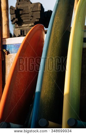Set Of Different Color Surf Boards In A Stack By Ocean.bali.indonesia. Surf Boards On Sandy Beach Fo