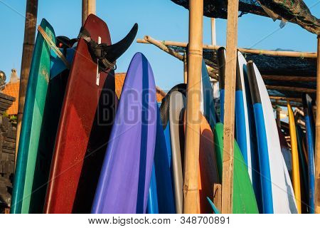 Set Of Different Color Surf Boards In A Stack By Ocean.bali.indonesia. Surf Boards On Sandy Beach Fo