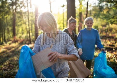Senior Women Friends Picking Up Litter Outdoors In Forest A Plogging Concept.