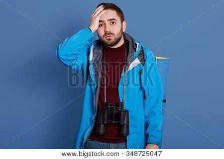 Close Up Portrait Of Young Handsome Man Standing Isolated Over Blue Background With Hand On Forehead