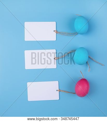 Easter Concept. Colored Eggs With Blank Tags Isolated On Blue Background Top View