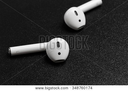 Air Pods With Wireless Charging Case. New Airpods 2019 On Black Background. Entangled 3.5 Headphones