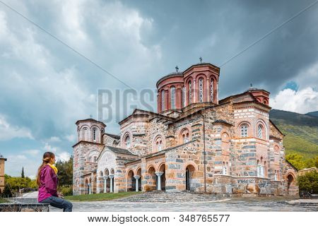 Tourist woman visiting the monastery of Timios Prodomos in Greece looking at the main church