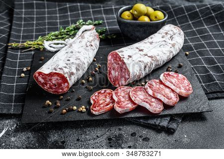Fuet Salami Cut In Slices And Rosemary. Traditional Spanish Sausage. Black Background. Top View