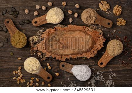 Gluten free flours in wooden spoons on a brown background
