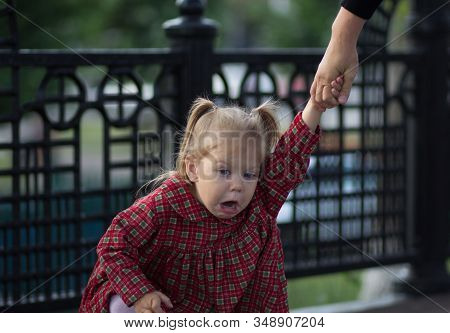 Funny And Capricious Face Of Caucasian Child Holding The Mother Hand