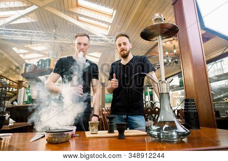 Hookah In The Process Preparations. Two Young Boys Prepare Hookah Sisha In Hookah Bar, Looking At Ca