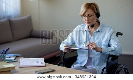 Travel Agency Consultant In Wheelchair Searching Appropriate Tour On Tablet