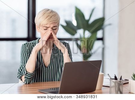 Rhinitis. Unhappy Lady Touching Nosebridge Having Runny Or Blocked Nose Sitting At Laptop In Modern 