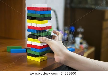 The Hand Dismantles The Tower Of Multicolored Wooden Bars. Concept: Children's Leisure, Board Games,