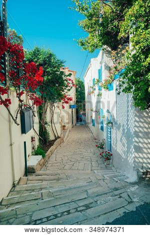 Beautiful Alley Street In Greece Authentic Style With Pink Flowers And Blue Shutters At Local Villag