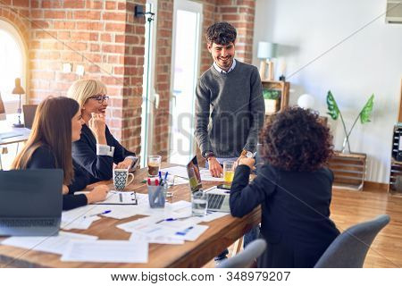 Group of business workers smiling happy and confident. Working together with smile on face. Young handsome man standing explaining documents at the office