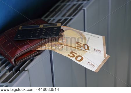 Calculator, Wallet And Banknotes Lie On The Radiator Of The Heating System, The Cost Of Heat, Utilit