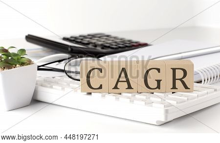 Wooden Cubes With Letters Cagr On The White Table With Keyboard And Glasses