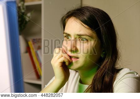A Woman Carefully Looks At The Tv Or Computer Screen, Bites Her Nails, Watches A Movie Or Tv Series.