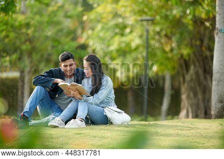 Friends Spending Time On College Campus And Reading Book Together