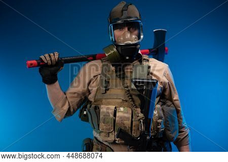 A Man In Military Clothes And A Gas Mask With A Red Fire Axe On His Shoulder