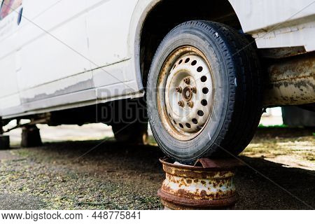 Old Rusty Car Wheel. Cracked Tires And Rusted Hubcaps.