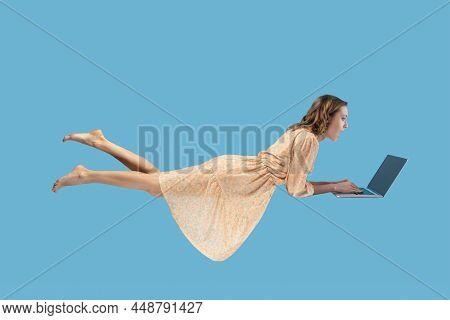 Hovering In Air. Surprised Excited Girl Yellow Dress Levitating With Laptop, Typing Keyboard, Readin