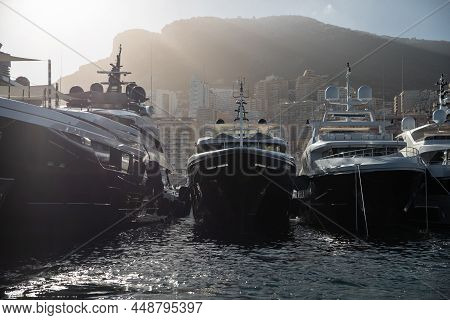 A Lot Of Huge Yachts In Port Of Monaco At Sunset, Mountain Is On Background, Glossy Board Of The Mot