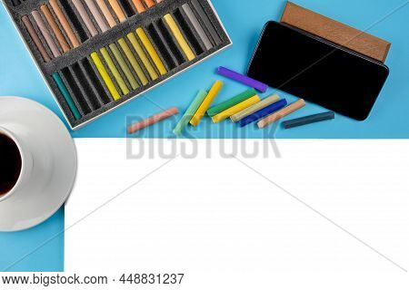 Flat Lay Soft Dry Artist Pastels, White Paper Sheet,black Smartphone By Side,coffee Cup On Saucer.on