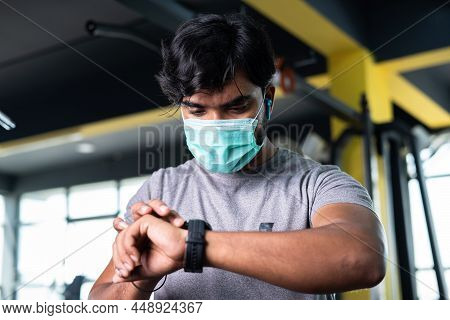 Low Angle View Of Young Man With Medical Face Mask Checking Brunt Calories Or Monitoring Hart Rate F