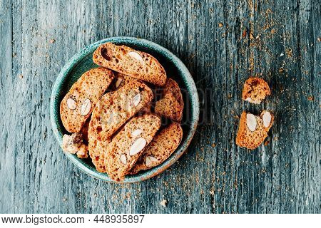 high angle view of some carquinyolis, almond biscuits typical of catalonia, spain, similar to italian biscotti, in a green earthenware plate, on a gray rustic wooden table