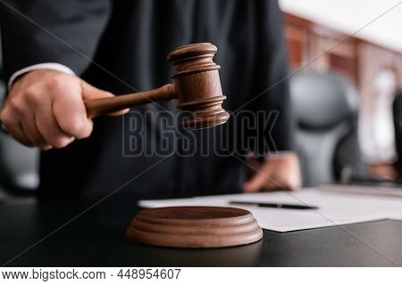 Partial View Of Blurred Judge Holding Gavel During Sentencing In Court