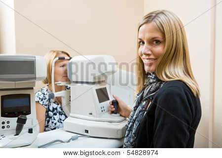 Young Optometrist measuring patients eye pressure with tonometer