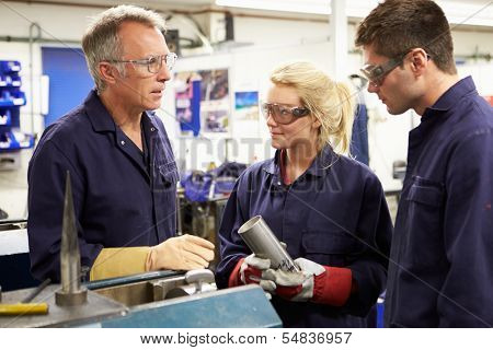 Engineer Working With Apprentices On Factory Floor