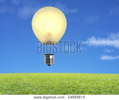 Single Glowing Lamp Balloon Flying Over Green Meadow With Sky