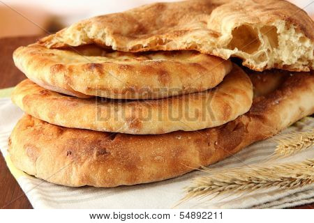 Pita breads with spikes on table on bright background
