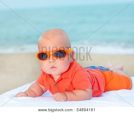 Cute baby wearing sunglasses on the sunbed