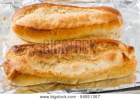 Freshly baked Italian-style bread batons, fresh from the oven and still on the baking sheet and tinfoil.