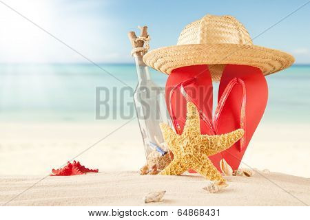 Summer concept of sandy beach, bottle with message, shells and starfish.