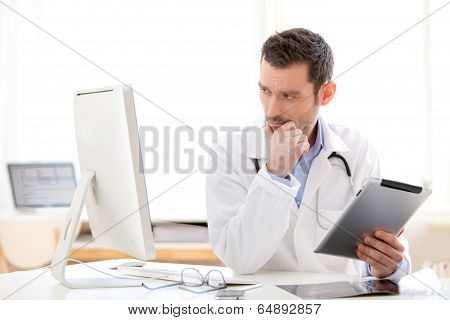 Portrait Of A Young Doctor Using Tablet At Work