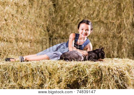 Bavarian girl playing with cat on hayloft
