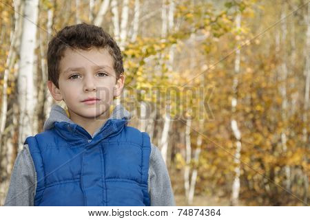 Little Smiling Boy In Autumn Forest.