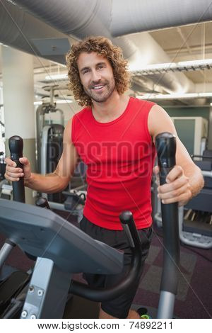 Portrait of a handsome young man working out on x-trainer in the gym
