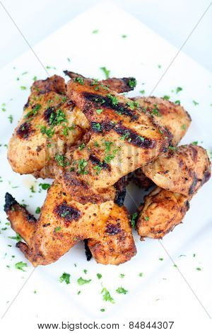 Cooked chicken wings in a sauce on a white plate