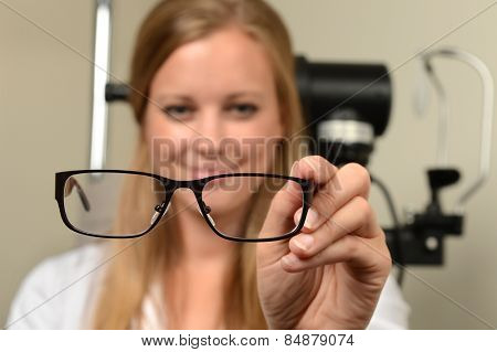 Female eye doctor holding glasses - focus on glasses