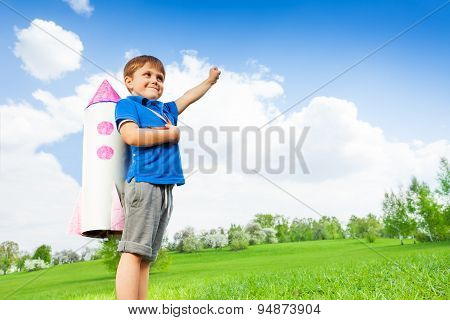 Boy wears paper rocket toy and holds arm up